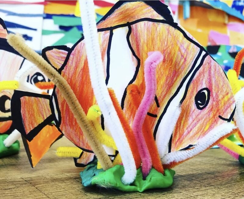 Paper fish sitting on a base of playdough with pipe cleaners to represent coral