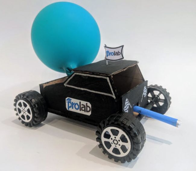 Car made from cardboard with bottlecap wheels and powered by a blue balloon