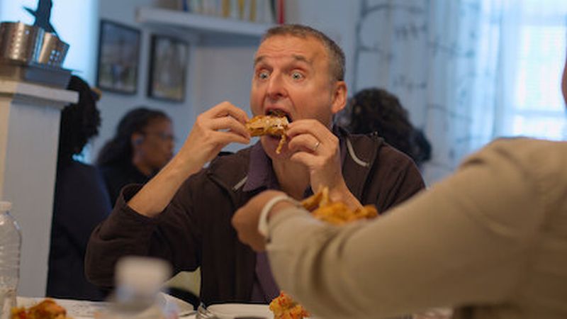 Phil Rosenthal eating a piece of chicken, from the Netflix show Somebody Feed Phil