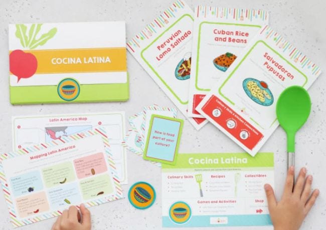 Child holding cooking tools and recipe cards from Raddish Kids (Educational Subscription Boxes)
