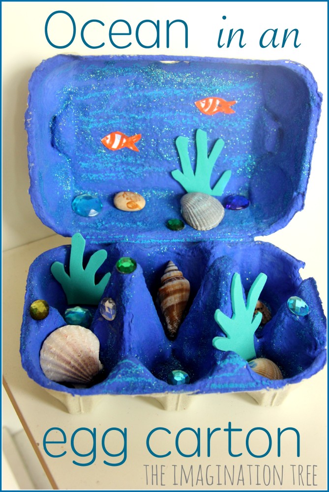 An egg carton is painted dark blue and filled with shells and has sea creature stickers stuck to it.