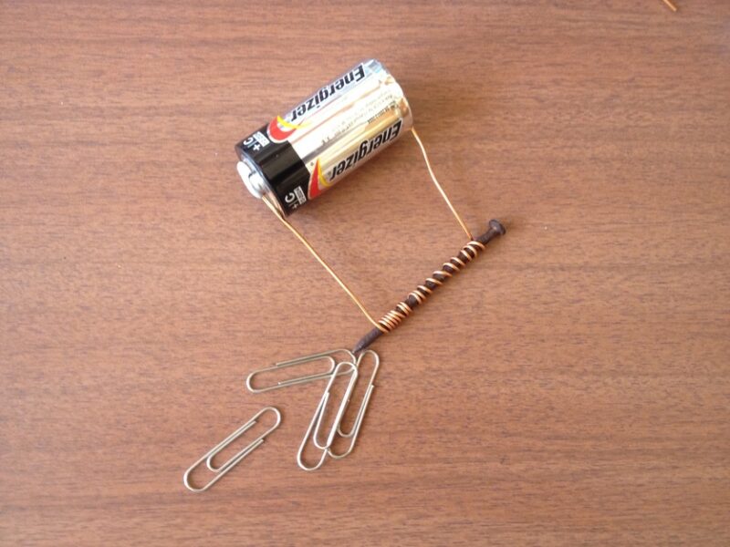 battery with copper wire wrapped around a nail for an electricity experiment 