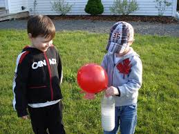 two boys holding a balloon and a jug for a cause and effect lesson plan experiment