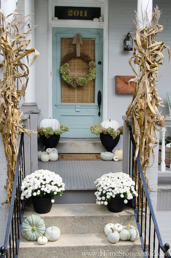 doorway and stoop decorated with fall flowers and painted pumpkins for a fall activity