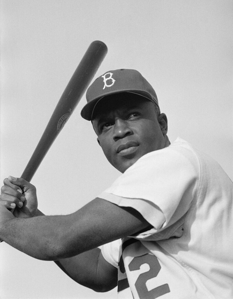 Black and white photo of Jackie Robinson swinging a bat