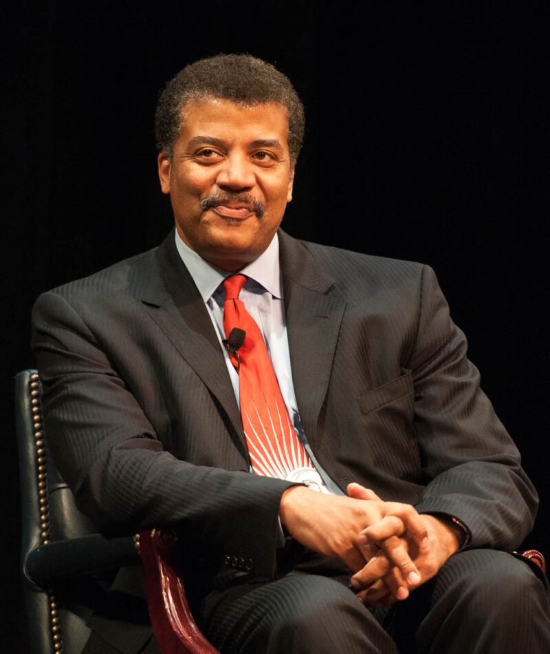 Neil deGrasse Tyson sitting in a chair on stage