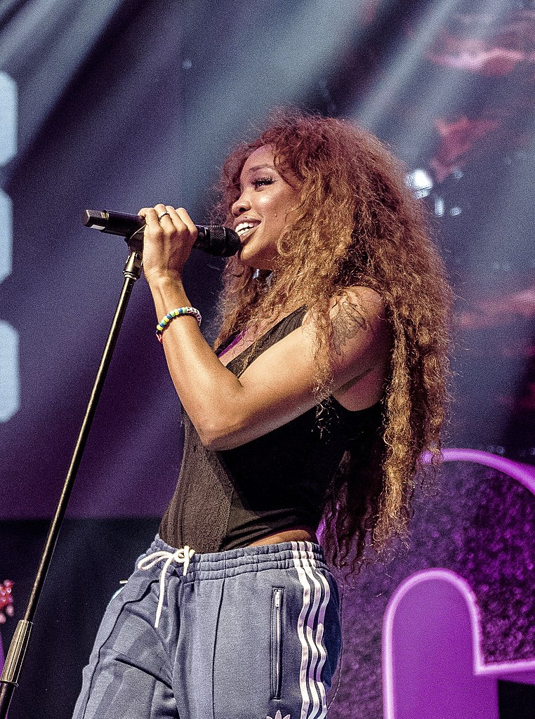 SZA on stage with a microphone and purple chair in the background