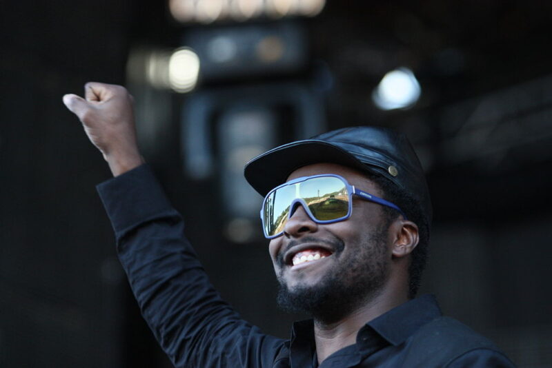 will.i.am wearing sunglasses and a black cap and shirt