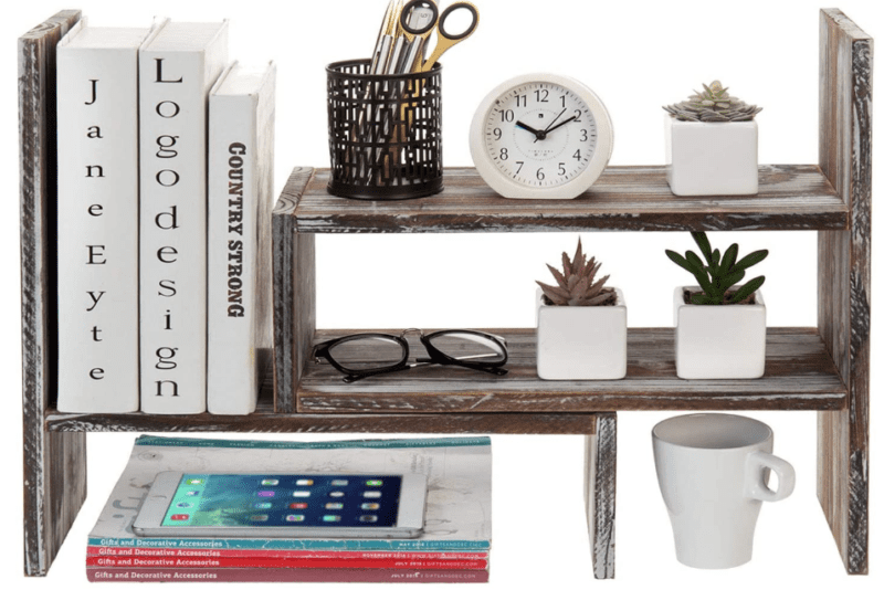 A rustic wooden organizational shelf with miscellaneous items on it such as books, succulents, a clock, and a mug used to exemplify the storage capabilities of the item.