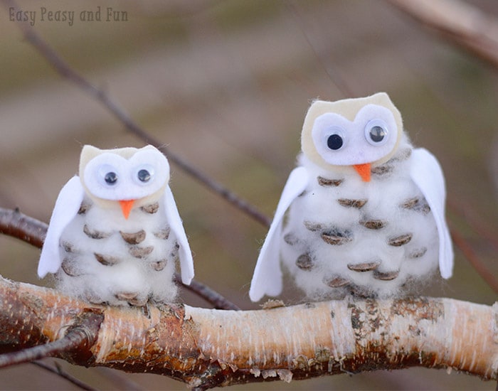 Two DIY owls made from pinecones and cotton balls perch on a branch