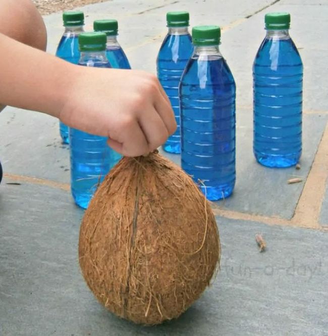 Water bottles filled with blue water, and a child's hand holding a coconut