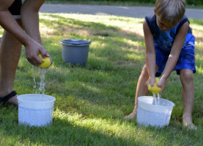 Kids using sponges to fill buckets with water (Field Day Games)