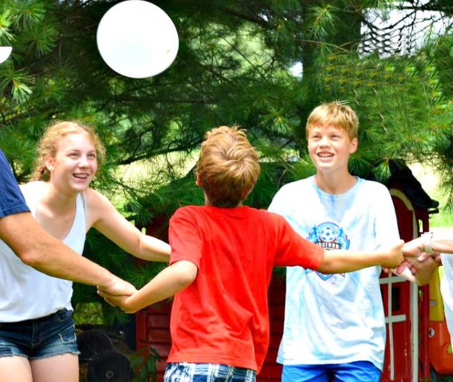 Students holding hands try to keep a balloon in the air without letting go of each other in this fun field day game.