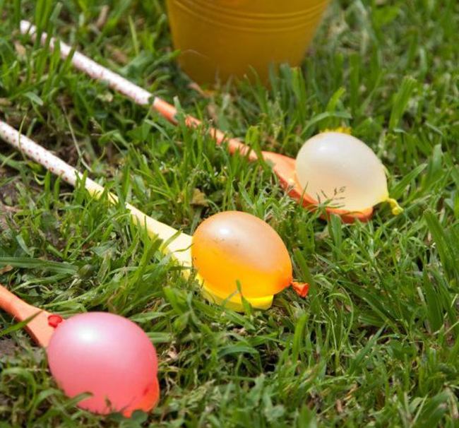 Small water balloons balanced on wooden spoons decorated with washi tape