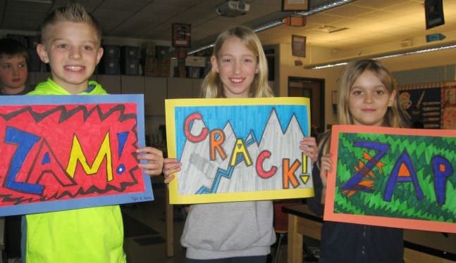 Fifth grade art students holding illustrations of the words Sam, Crack, and Zap