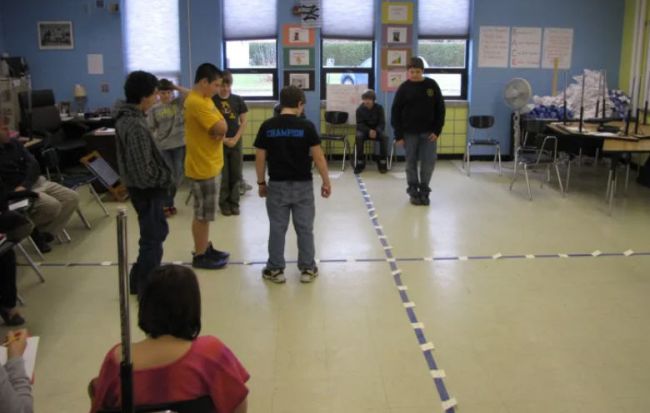 Students standing on a classroom floor marked to represent a coordinate plane