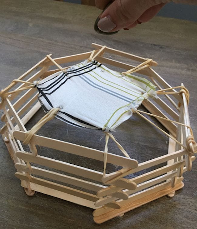 Miniature trampoline built from wood craft sticks, rubber bands, and fabric 