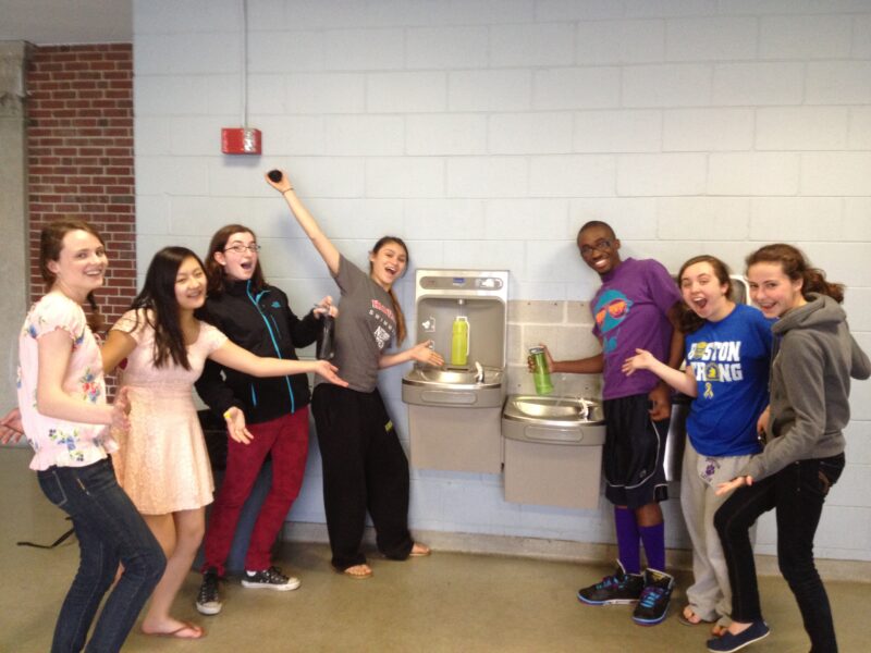 students standing around a water bottle filling station for a green school idea 
