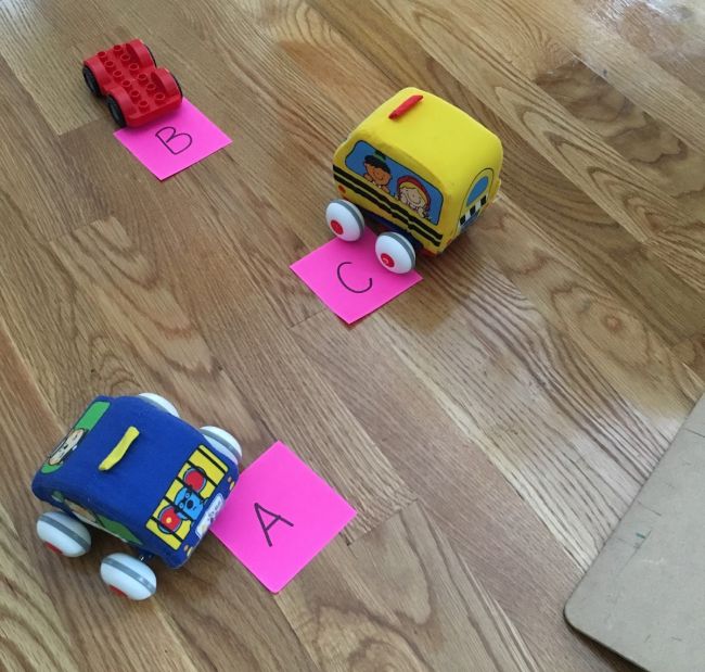 Three toy cars labeled with sticky notes marked A, B, and C (First Grade Math Games)