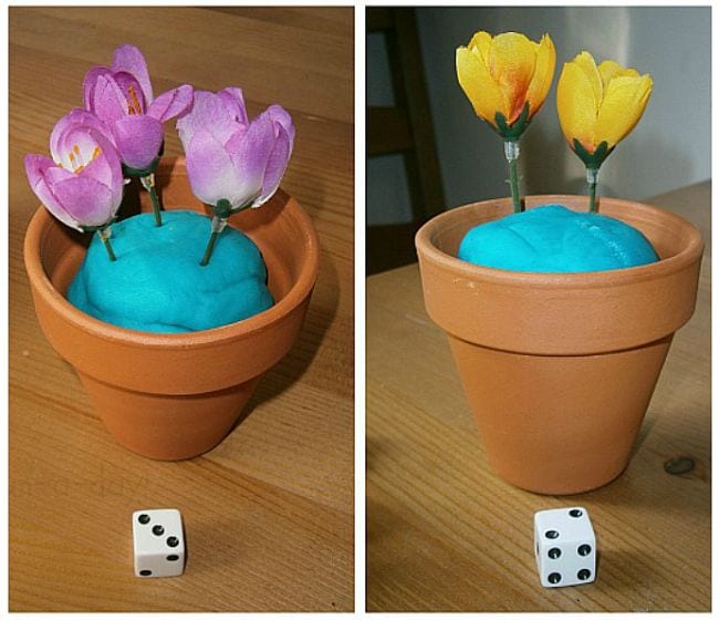 Flower pots with playdough soil, filled with artificial flowers matching the number shown on the dice nearby (First Grade Math Games)
