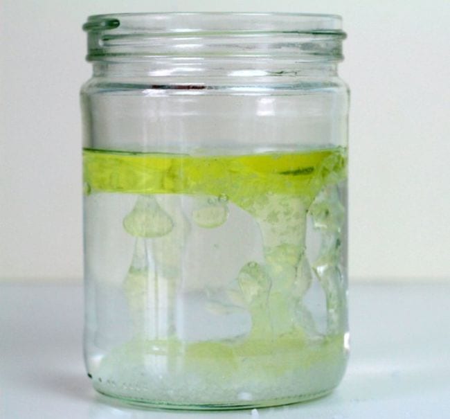 Glass jar filled with water and floating yellow oil