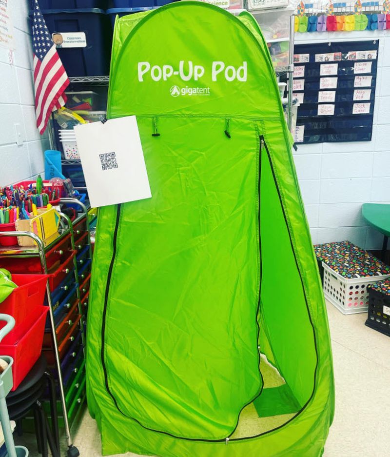 A lime-green popup tent in a school classroom with a QR code taped to it, used for recording Flip video responses