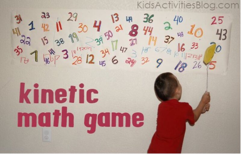 child with fly swatter hitting at letters on a wall 