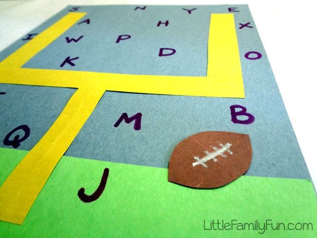 Yellow goal post surrounded by letters of the alphabet with a paper football (Football activities)