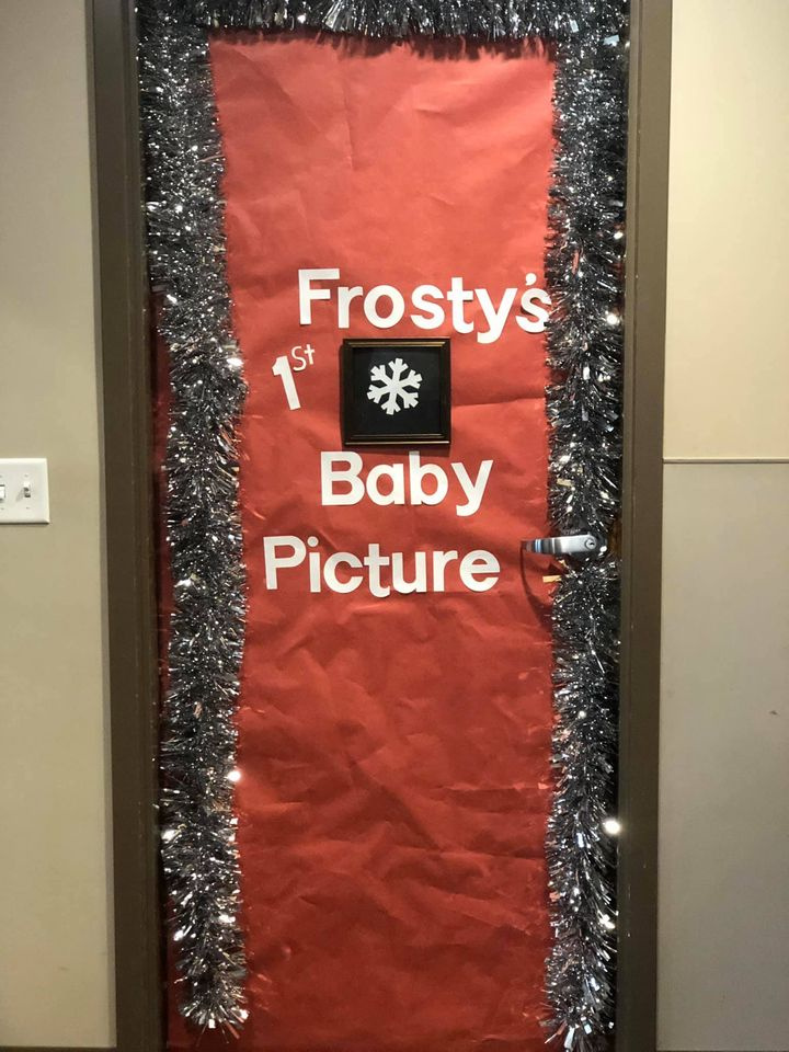 Holiday classroom doors include this one that is all red and has a tiny snowflake on it. Text reads Frosty's Baby Picture.