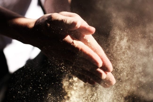 Student's hands covered in flour in a cloud of flour dust