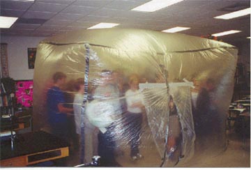 Students stand inside a large plastic encasing in this giant plant cell project.