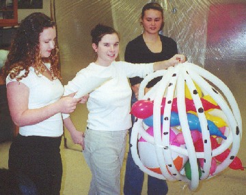 Three students are seen holding a giant plant cell nucleus created from inflated balloons in this example of a giant plant cell project.