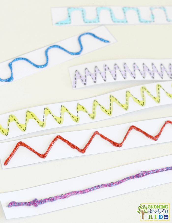 Strips of paper with straight and curvy lines outlined with glitter glue