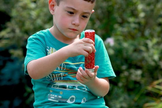 A young boy is mesmerized by a bottle filled with liquid and glitter