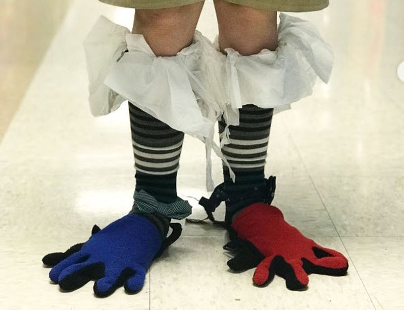 Child wearing gardening gloves on their feet, with tissue paper tucked into the tops of their socks