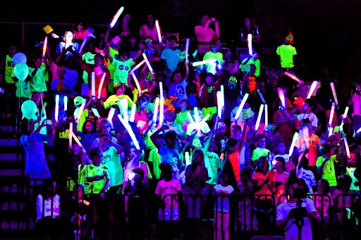 Students in a black-lit room wearing neon clothing, as an example of pep rally activities and games