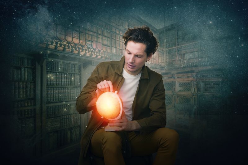 Man holding a glowing globe in a misty library