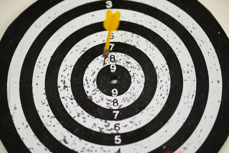 Black and white target with yellow dart near the bullseye.