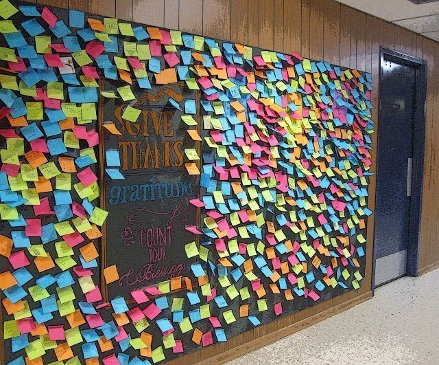 Wall covered with post-its that have notes of gratitude on them 