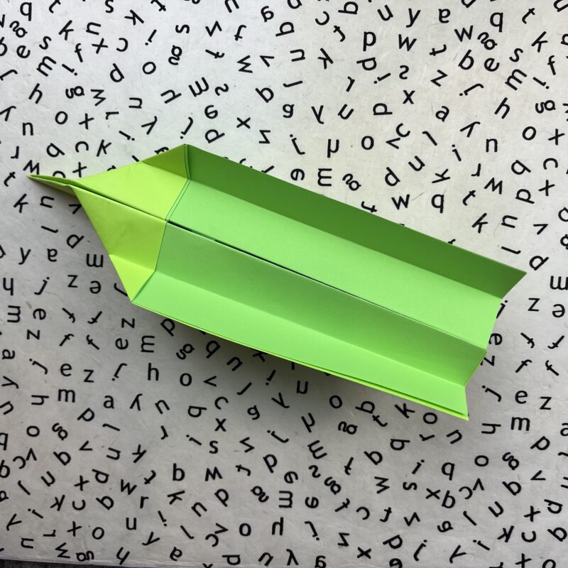 Fished green glider plane after following direction for how to make paper airplanes.- how to make paper airplanes