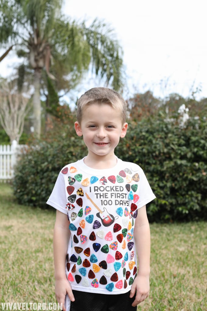 100th Day Shirt: Guitar Picks A little boy is shown wearing a t-shirt with guitar picks all over it. It says I Rocked the First 100 Days!