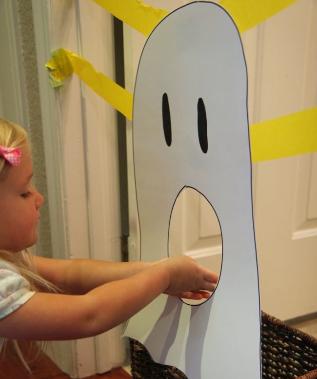 Halloween activities can be hands on like this one. Young student feeding construction paper letters through a large paper ghost's mouth (Halloween Activities)