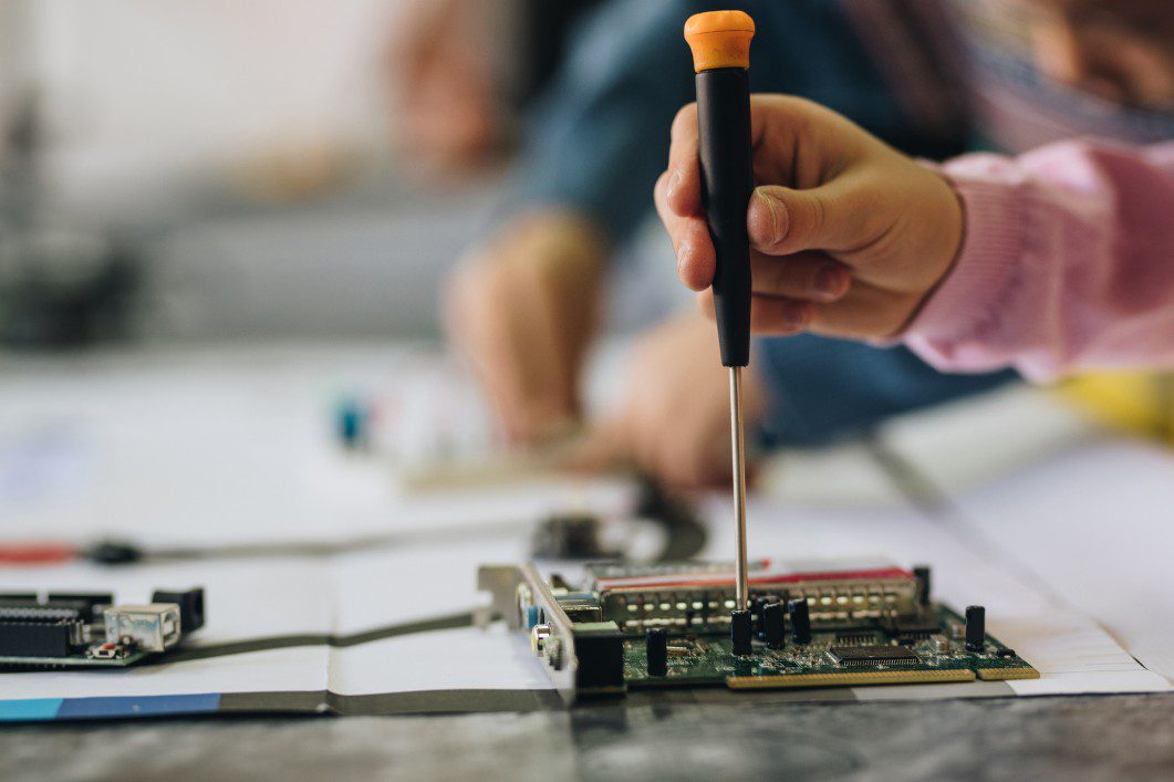 Kid's hand with screwdriver working on STEM project