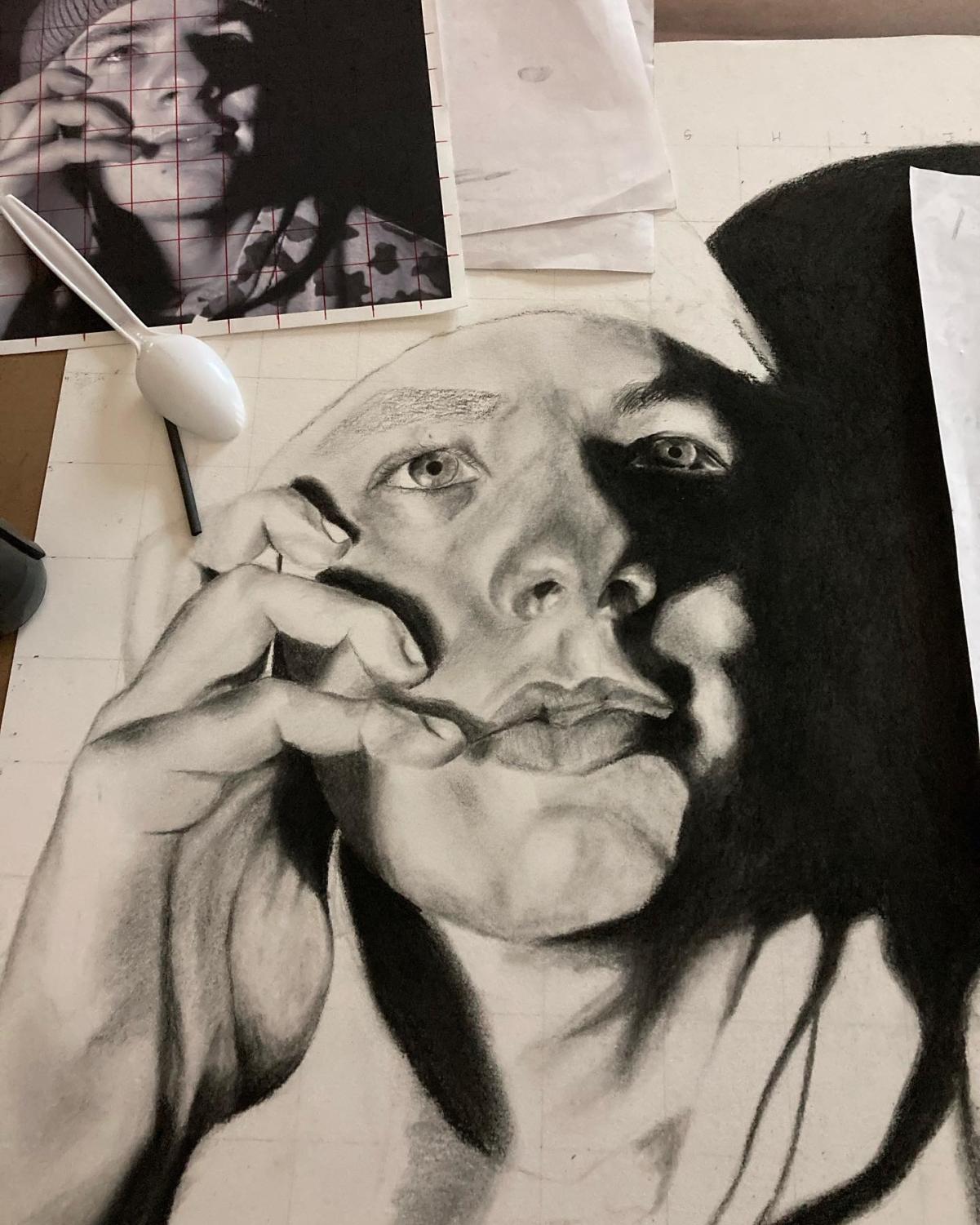 A black and white drawing shows an up close of a person's face with their hands on the side of their face. 