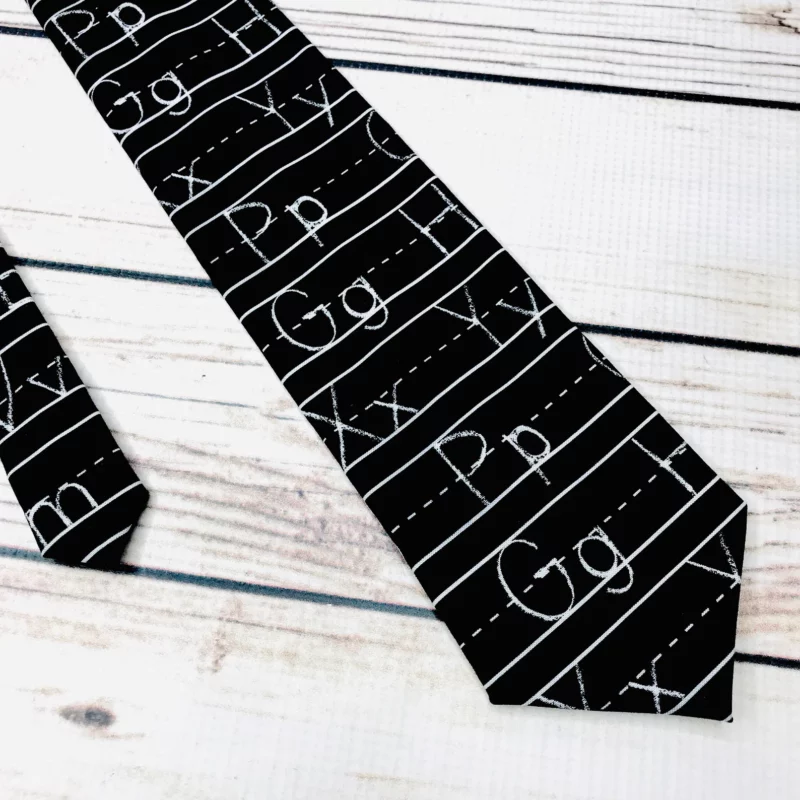 Tie that looks like a chalkboard with handwriting letters of the alphabet.