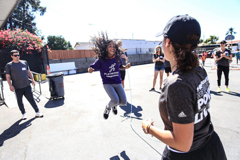 Kids are seen playing jump rope. 