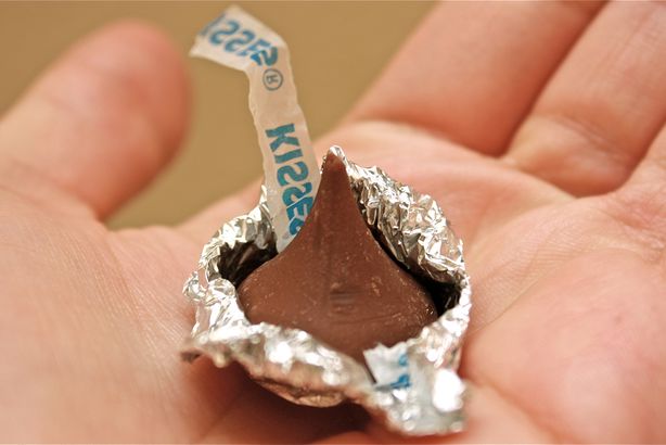 Picture of a child holding a Hershey kiss candy in the palm of her hand, as an example of second grade science experiments. 