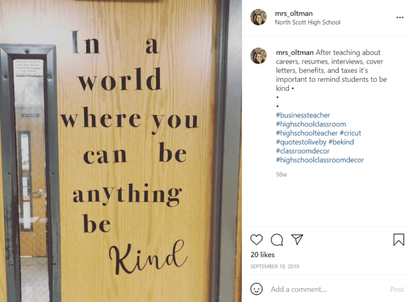 A brown classroom door with a thin vertical widow with the phrase "In a world where you can be anything be kind" in black letters.