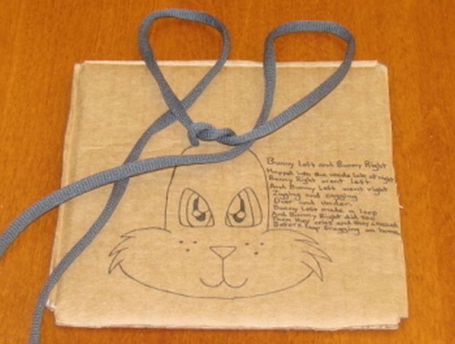 Cardboard with bunny face and shoelace loops to represent ears (How to teach kids to tie shoes)