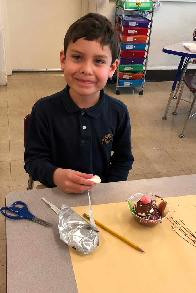 A little boy is shown working on his ice cream sundae sculpture (second grade art)